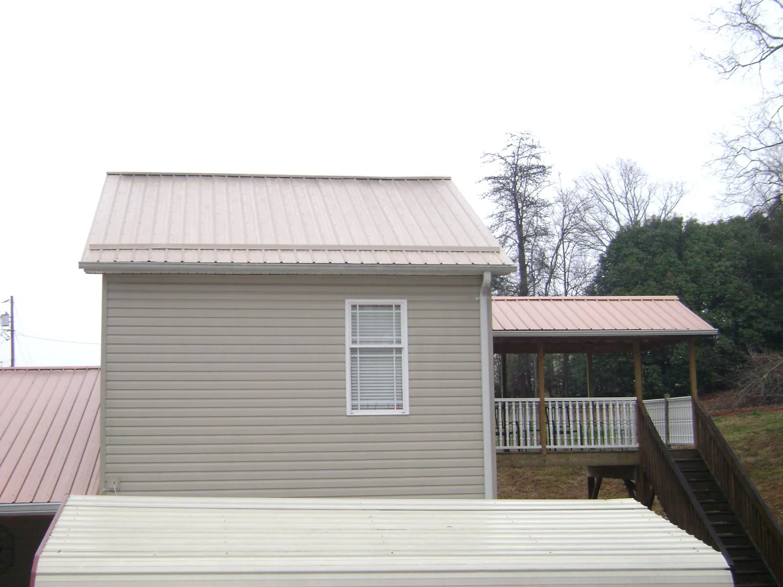 Tan metal roofs on a two story addition and attached porch, from a Roof Replacement job in Three Rivers