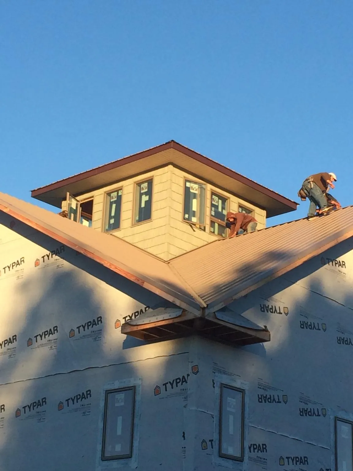 Roofers working around a rooftop cupola on a new metal roof at sunset — Roof Waterproofing in Three Rivers by Roofing Brothers